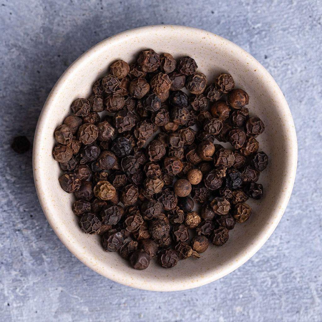 Top view of a bowl that is full of Soeos whole black peppercorns.